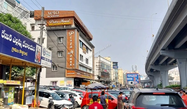 Busy street view featuring the famous Pista House and Veto Bar & Kitchen near the flyover accessible from Prestige Golden Grove