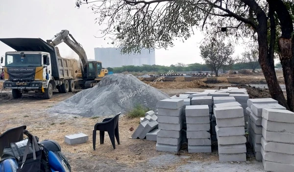 Concrete blocks and construction aggregates staged in the foreground while heavy machinery operates in the background at Prestige Golden Grove