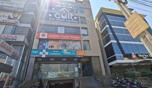 A multi-story commercial building housing a Cult.fit gym, Bank of Baroda, and Apollo Pharmacy, ensuring residents of Prestige Golden Grove have access to prime utilities