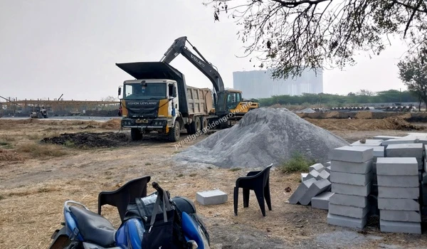 Earthmoving equipment loading construction debris and soil into a dump truck near large gravel piles at Prestige Golden Grove