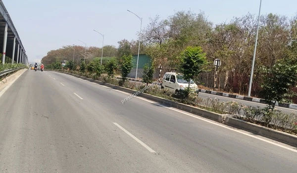 A street-level perspective taken on March 03 , 2026, illustrating the wide, smooth commuting paths and lush median landscaping along the Nehru Outer Ring Road adjacent to Prestige Golden Grove.