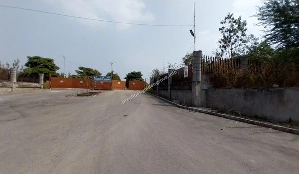 View of the main access road and site barriers at the Prestige Golden Grove project site in Hyderabad